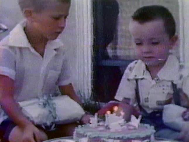A boy spins a birthday cake in front of him