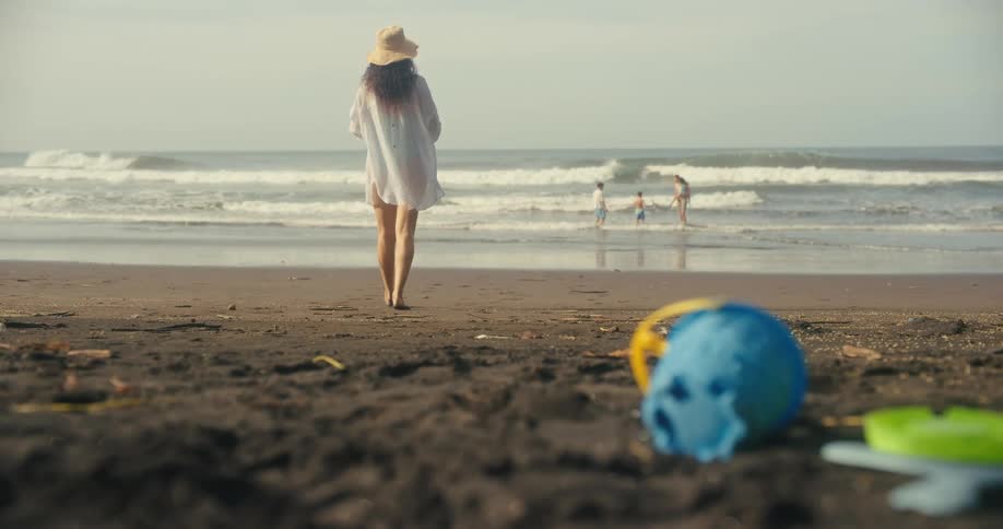 A family having fun on the beach with a woman walking toward her children and husband who are in the water