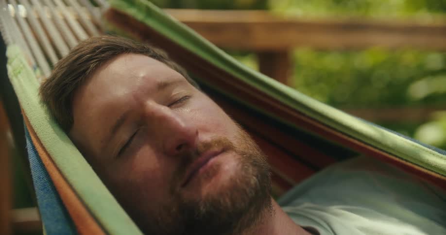 The man is sleeping in the hammock