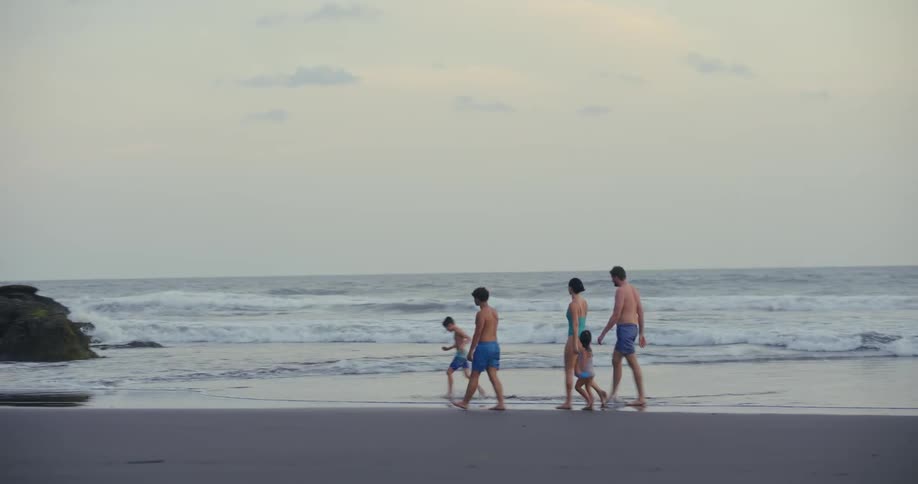 Family walks along the beach during the daytime together