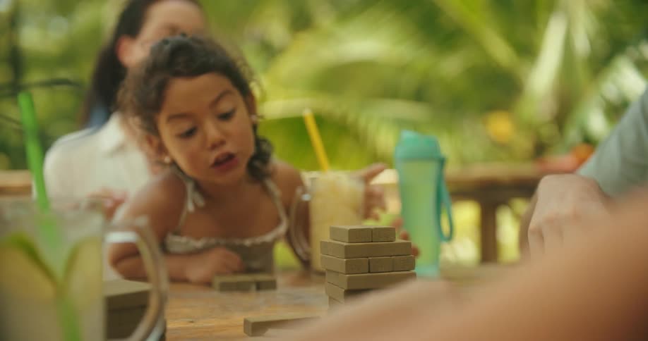 A female adult and a female child are happily enjoying drinks outdoors while playing a game with others