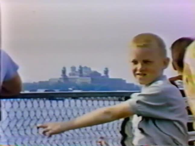 A young boy is standing by a fence moving back and forth