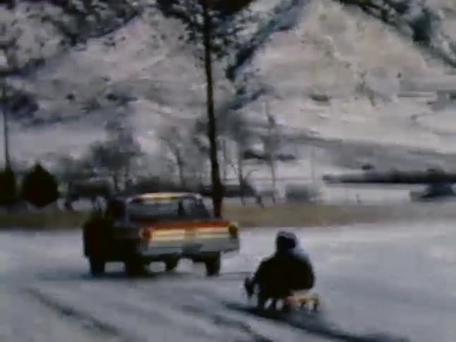 A car is pulling a person on a sled