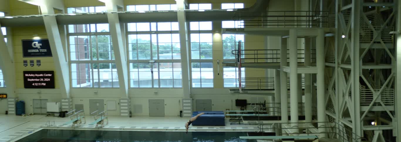 Person diving in slow motion off a high dive in an indoor swimming pool