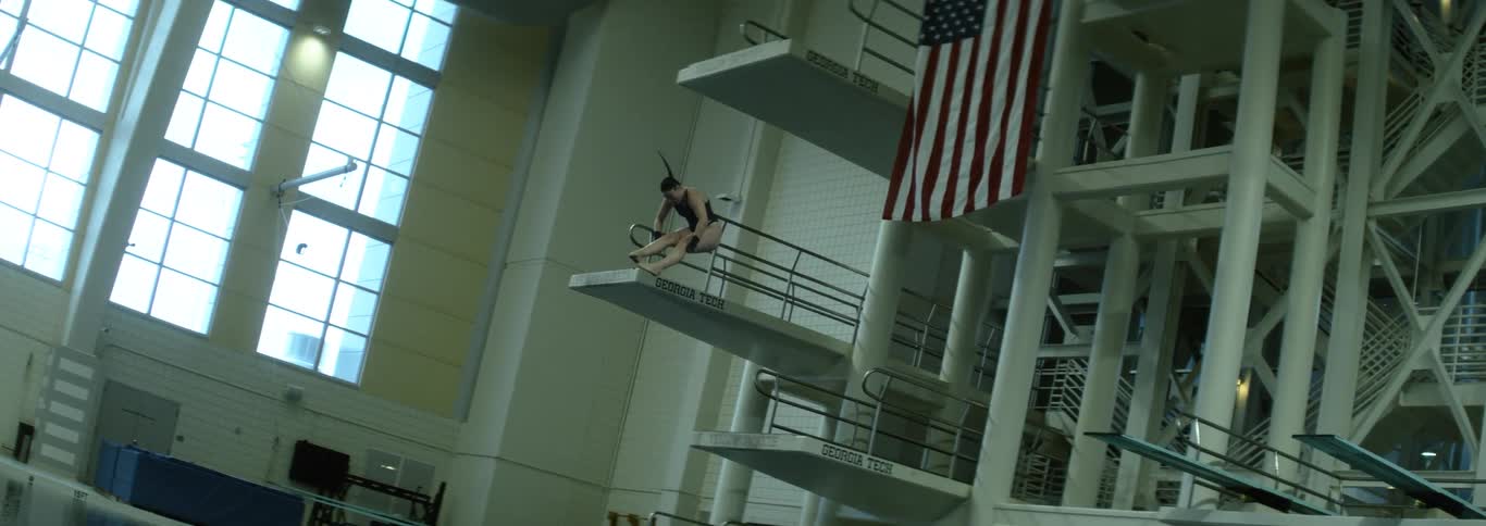 The woman flips while diving in the pool