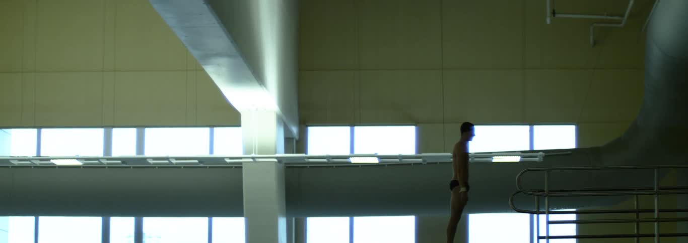 Athlete standing upright on the diving platform in a welllit indoor facility