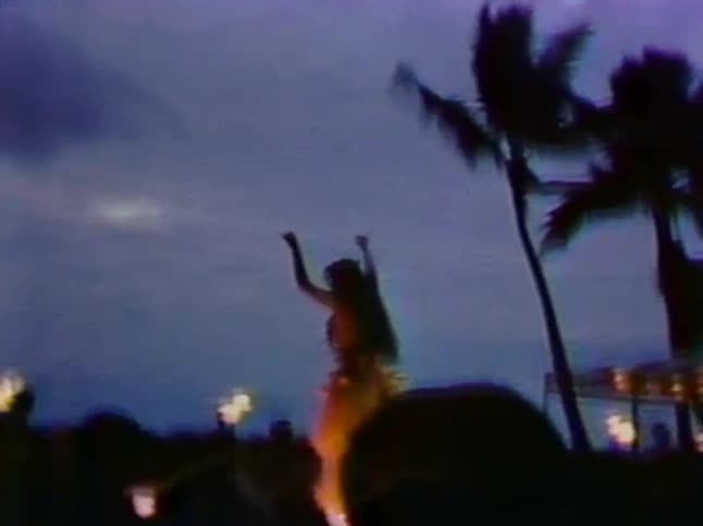 A woman is hula dancing under a cloudy sky