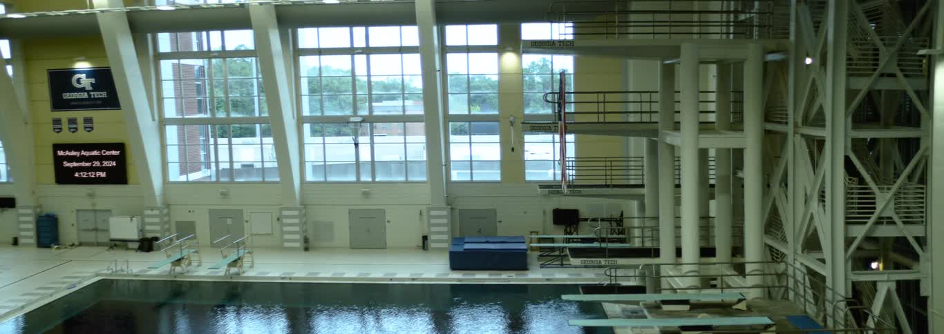 Large windows let sunlight in to shine onto a swimming pool and several diving boards