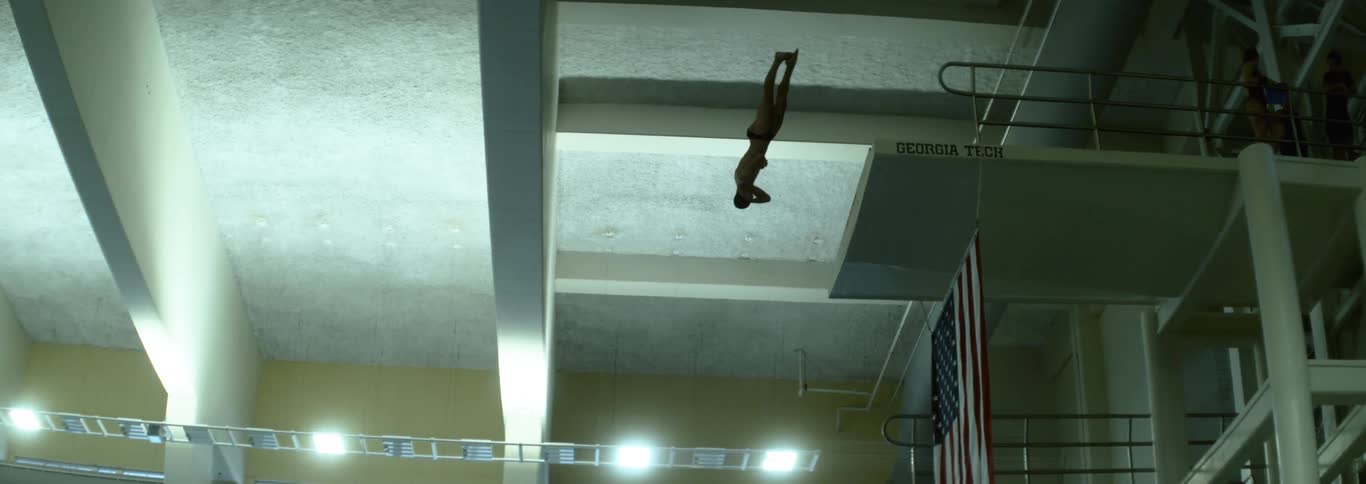The diver twists as they dive down into the pool