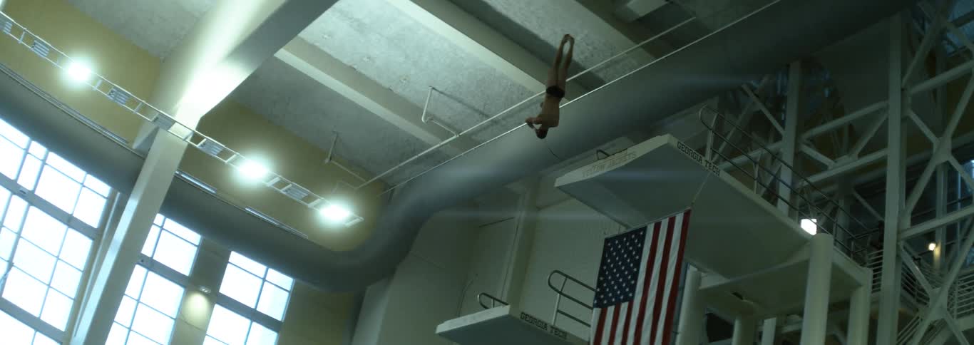 Competive diver spinning in mid air in slow motion off the high dive
