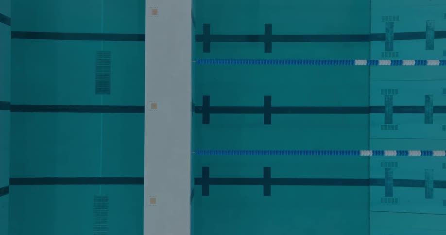 An elevated view of a swimming pool shows dark blue lines on the bottom and a variety of lane dividers floating on the turquoise water