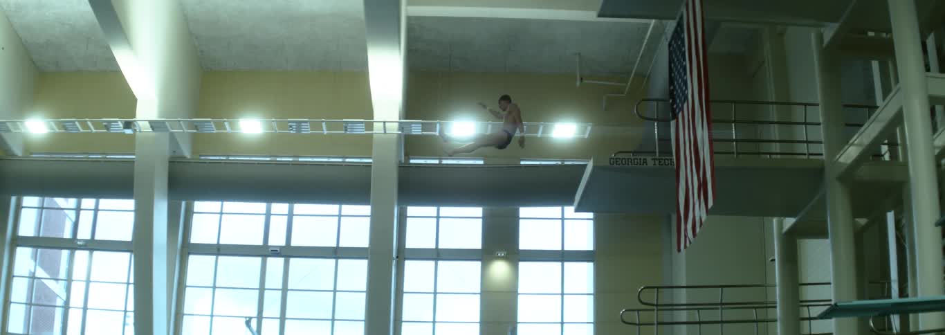 The man dives from the high platform into the pool
