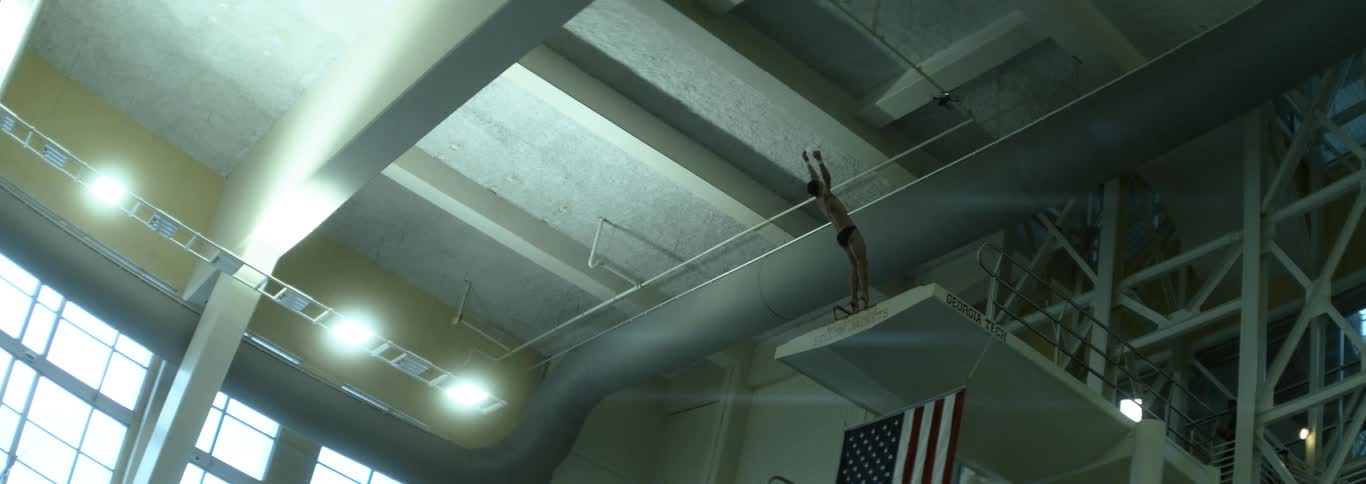 Athlete begins a dive from the platform at the indoor aquatic center