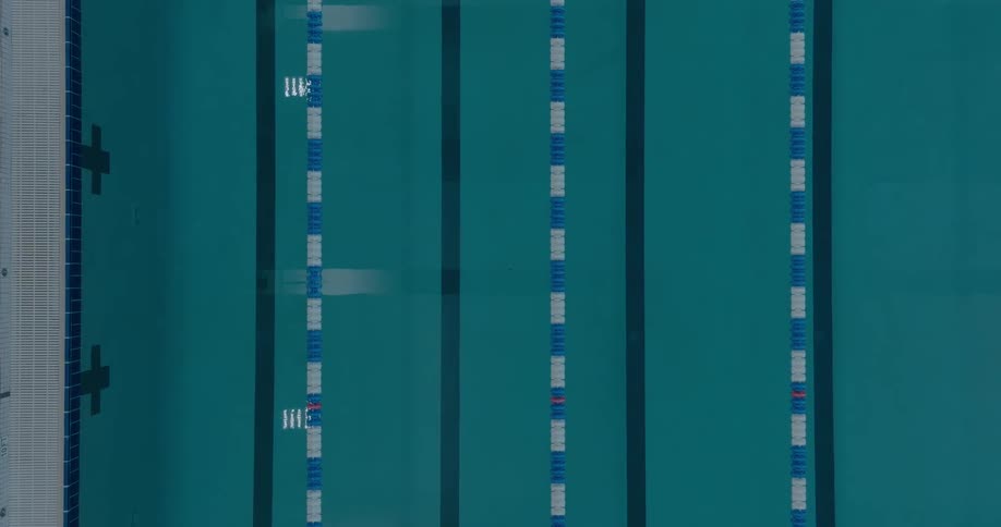 An overhead view of a swimming pool with lanes marked by a dark blue line on the bottom of the pool