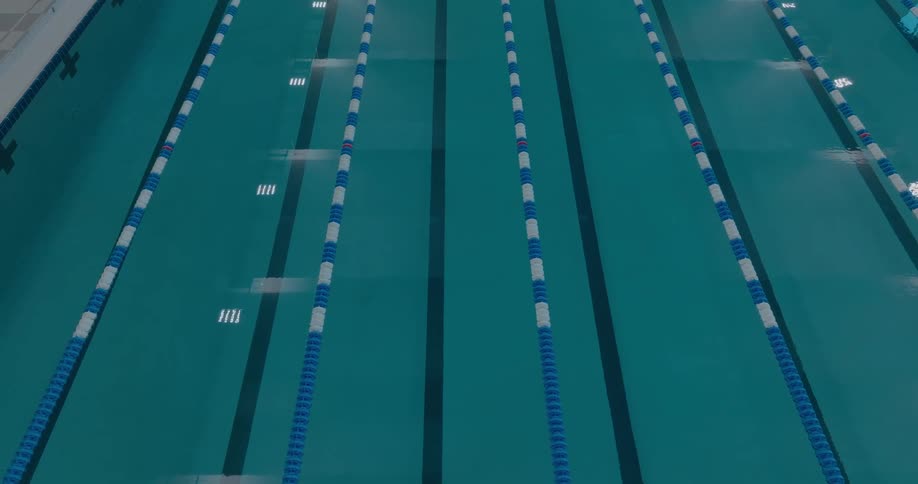Blue and white floating lines divide a large interior swimming pool into lanes