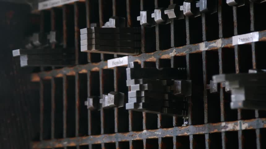 The image shows metal type pieces labeled and neatly stored on shelves