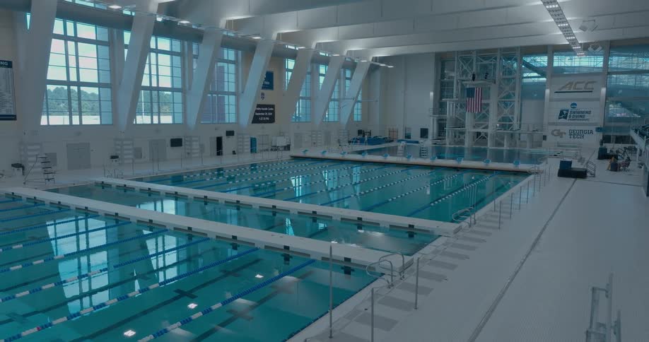 Indoor olympic pool at georgia tech with aligned lanes and a diving platform in the background