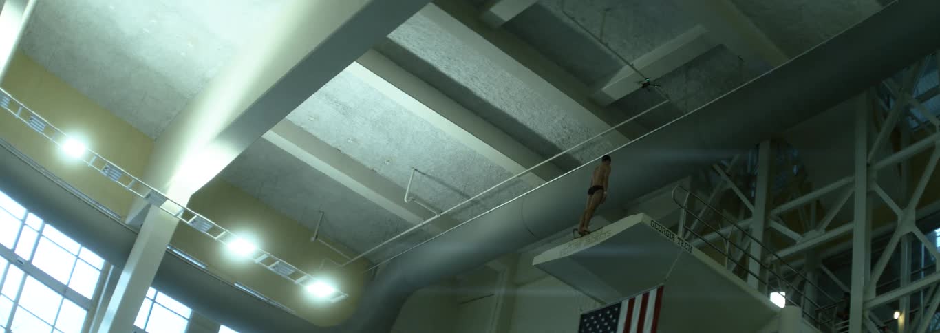 A male divers stands motionless atop a very tall diving platform
