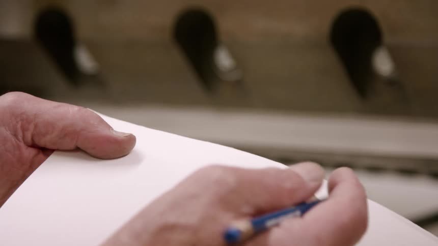 A persons hand writing with a pen on a blank sheet of paper