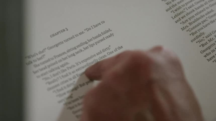 Person reading a book traces the words with his finger