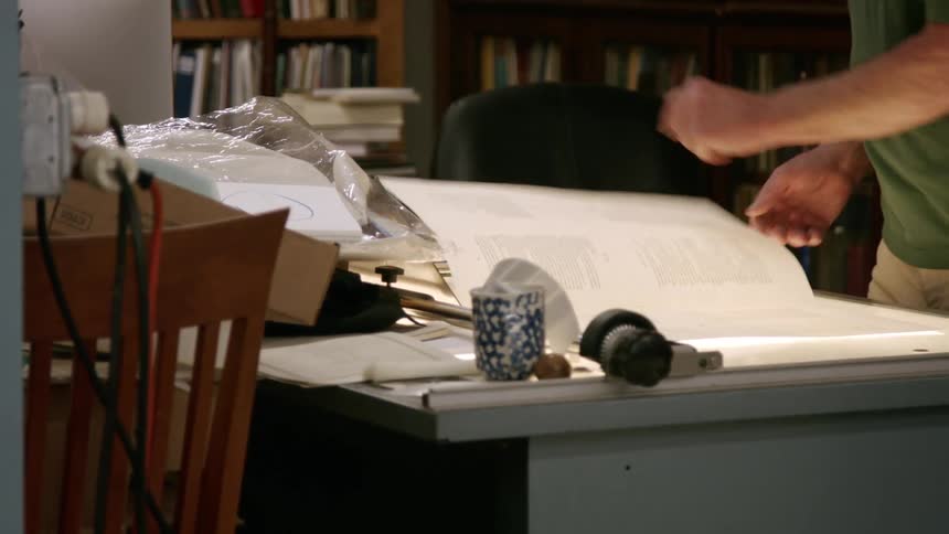 The man carries a large sheet of paper in the office