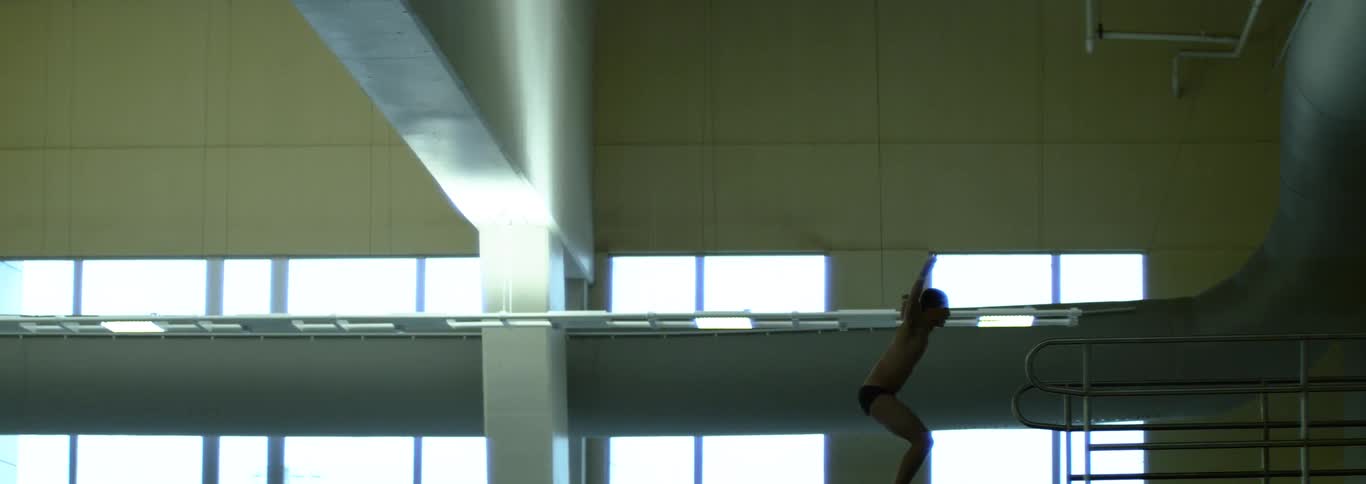 Athlete prepares to dive from a platform in an indoor facility