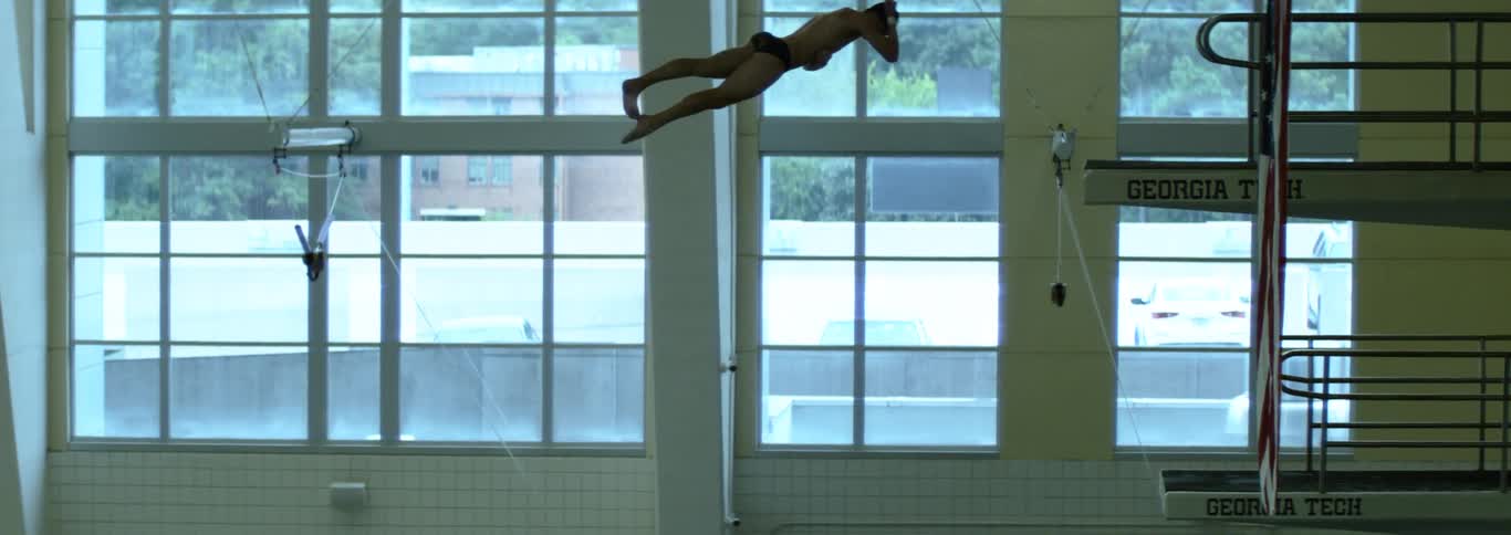 The video shows an indoor swimming pool with multiple diving platforms a large american flag hangs from the ceiling and a sign for georgia tech is visible in the background008