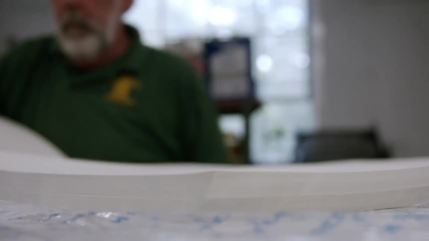 A man places a stack of white piece of paper over others