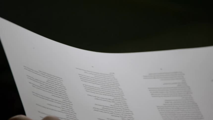 A person holds a large sheet of people covered in words