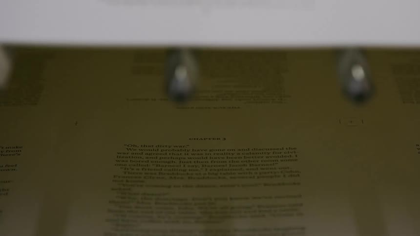A page from a book is visible with the camera zooming in on a chapter titled chapter 3 the text on the page is about a war and has quotes from two different people