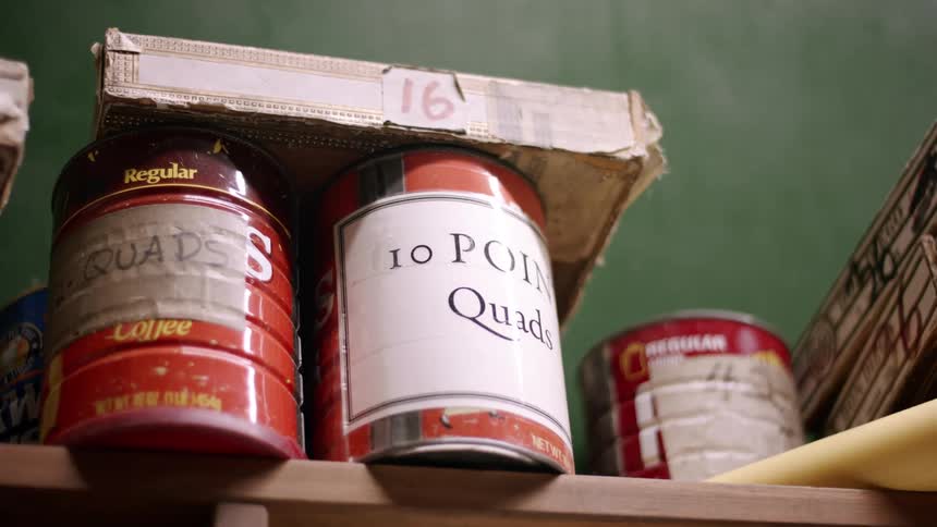 Several metal coffee cans on a shelf are relabeled with different contents