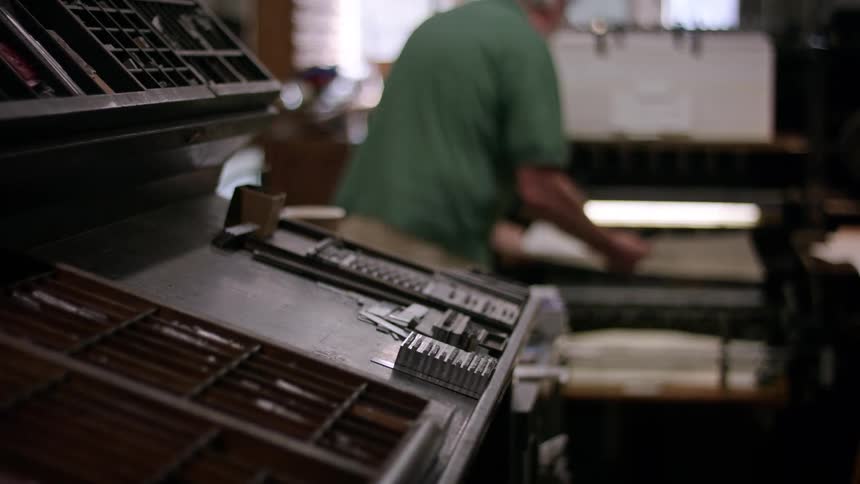 Typography workshop with movable type in focus and a man in the background