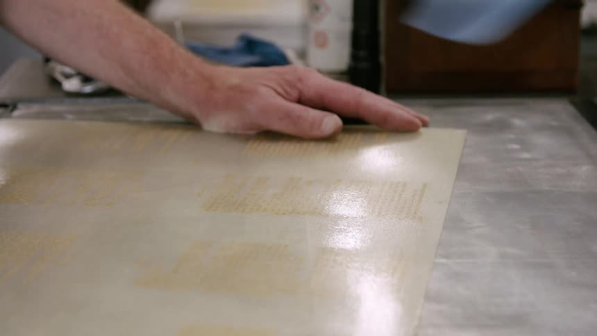 Hands remove blue sheet from printing matrix