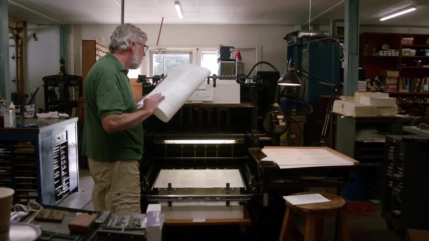 The man watches the large machine print pages
