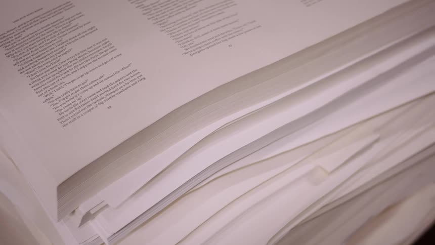 A shot focuses on a stack of printed pages in a book highlighting the text on the pages the camera slowly moves across the pages of the book