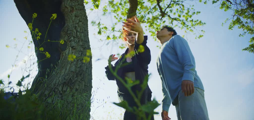 A shot focuses on a man and a woman as they dance and spin together in a field of bright yellow flowers they reach their arms out enjoying a playful and joyful moment in the sun