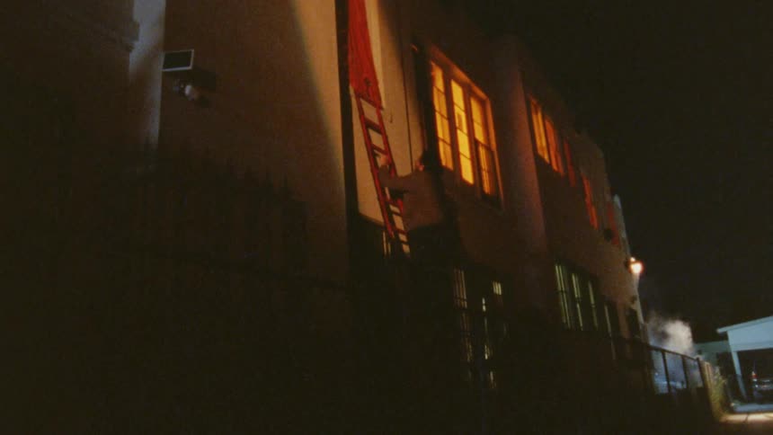The man climbs the long red ladder against the building