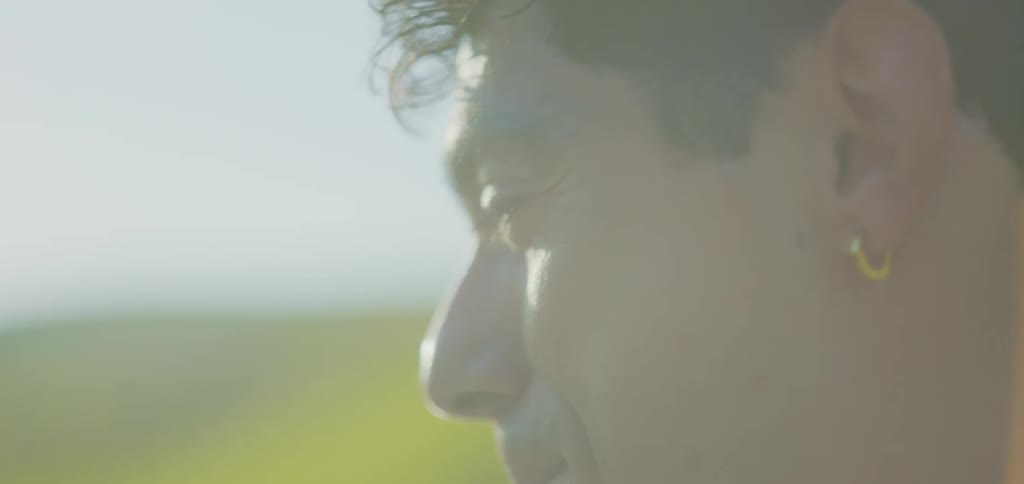 Side profile of a smiling man lit by the sun with a blurred background