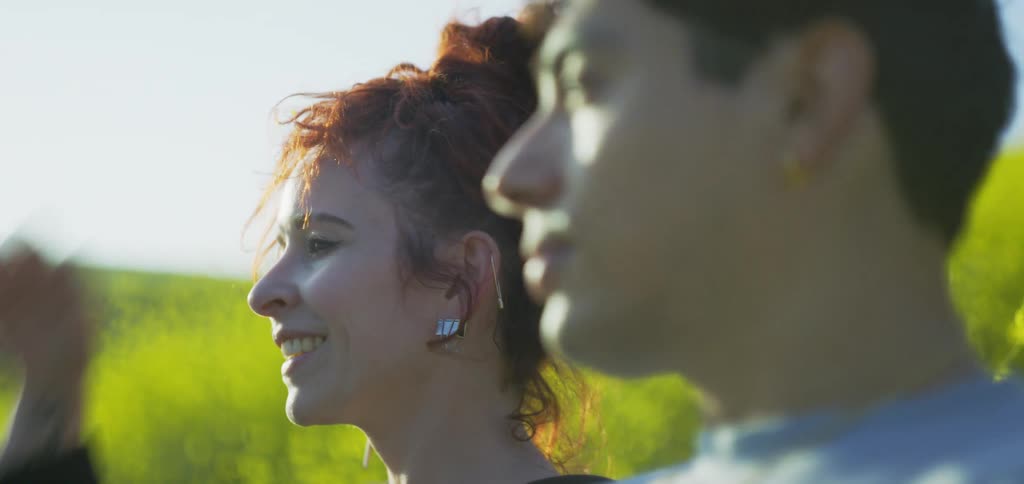Smiling woman talks outdoors with a man blurred in the foreground