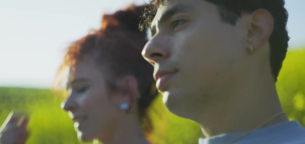 Smiling woman looks at a man while talking outdoors in the middle of a green field