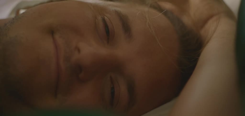 The man smiles while laying down