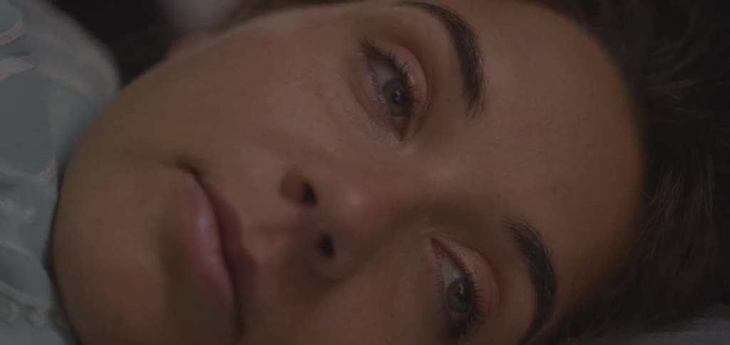 Couple lying together with the woman smiling softly while receiving a kiss on her face