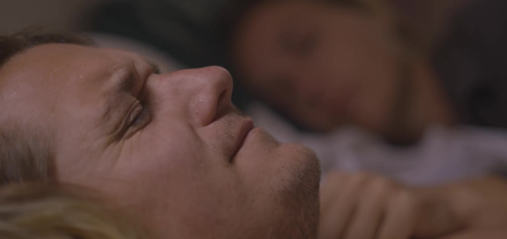 Man lying down receives affection from a woman in the background