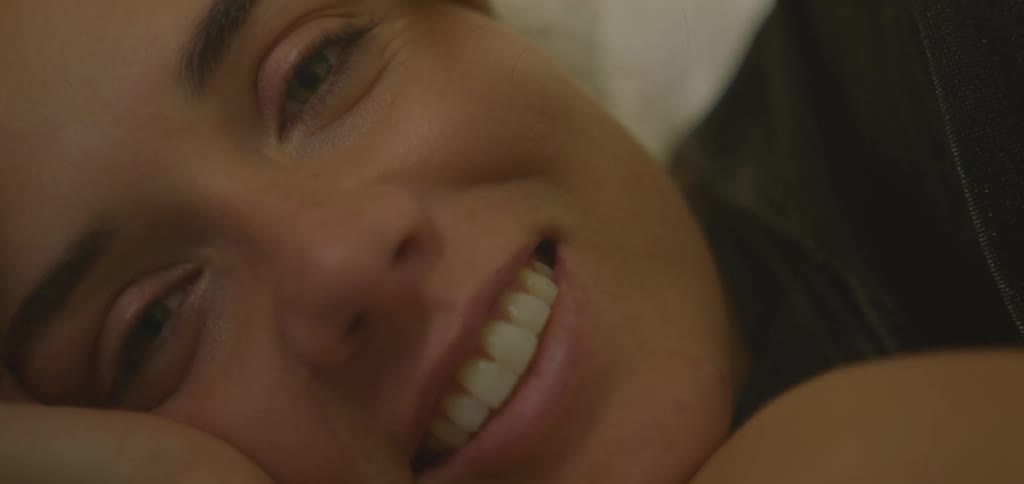 Young white woman lying down and smiling while talking indoors during day time