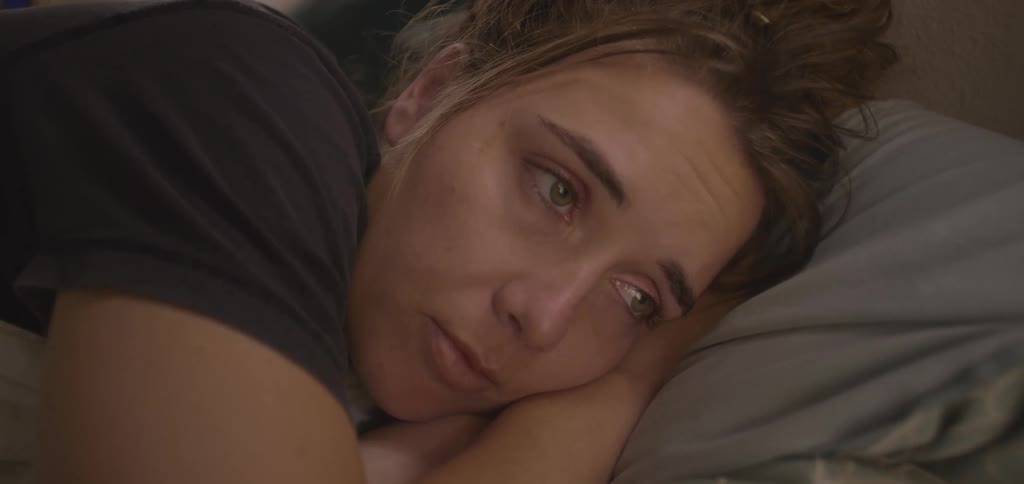 Woman lying in bed with a tired expression and distant gaze