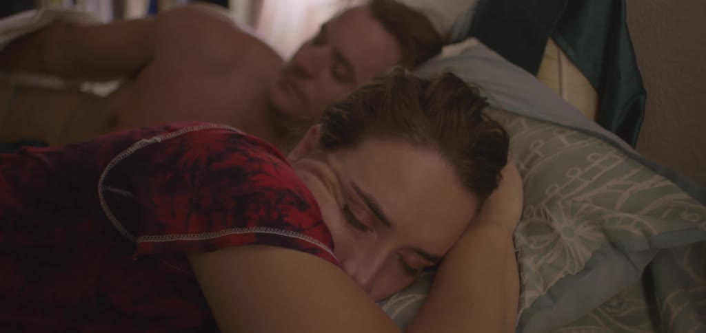 A couple lying in bed the man trying to get close to the woman but she wants to sleep