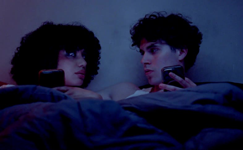 A couple a man and a woman lying in bed each using their own phone