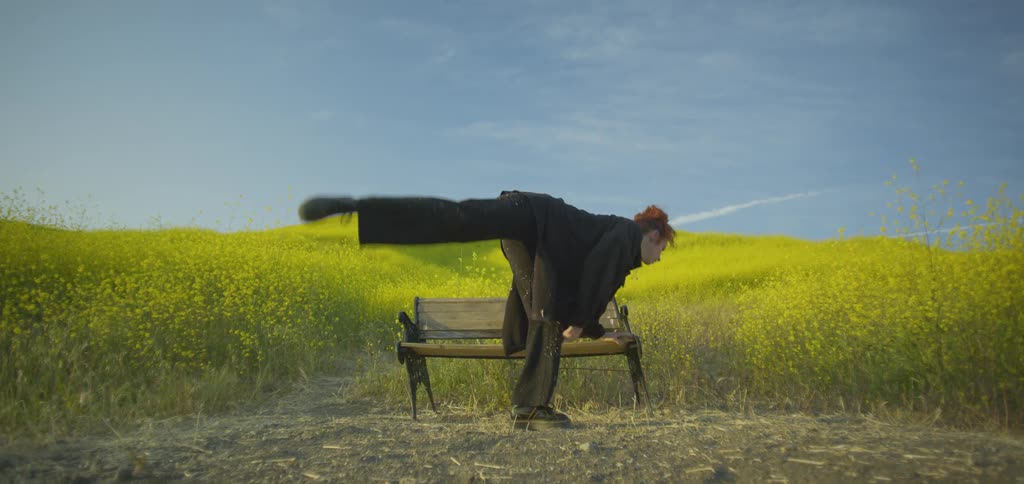 The woman break dances near the field full of flowers