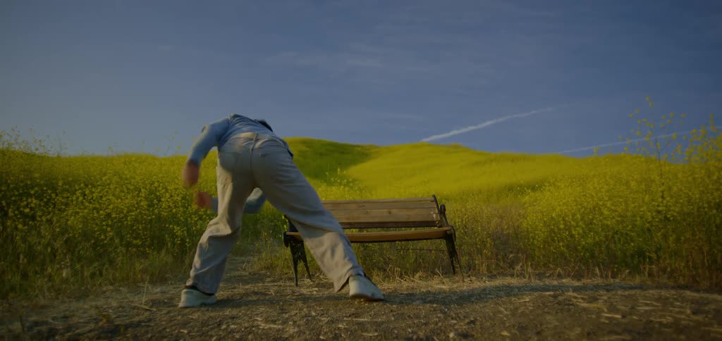 A man stands in a field and jumps up and down with his arms and legs moving out and in