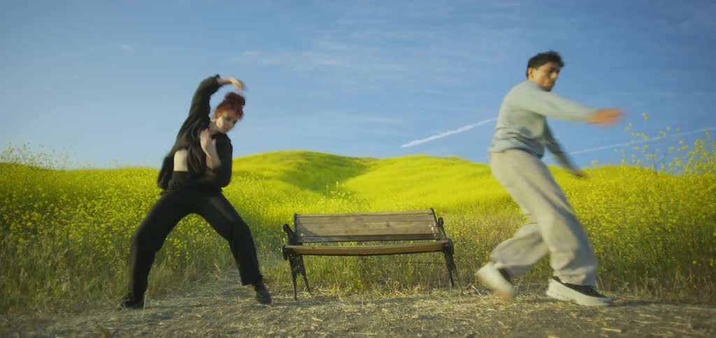 A man and a woman dancing freely near a bench in the middle of nature